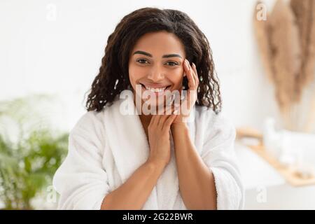 African Female Touching Face Smiling To Camera Posing In Bathroom Stock Photo