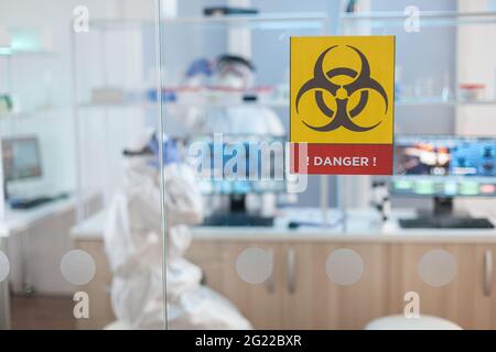 Team of chemist doctors wearing protection suit working in danger area of medical research laboratory. Group of doctors examining vaccine evolution using high tech for diagnosis against covid19. Stock Photo