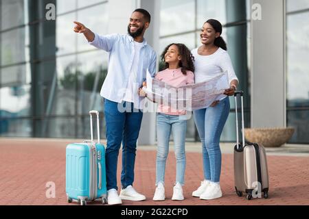 Happy black family traveling with kid, holding map Stock Photo