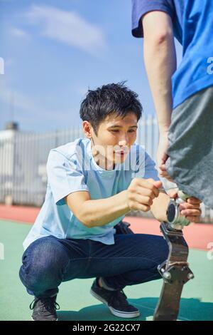 Japanese prosthetist working with amputee on rooftop Stock Photo