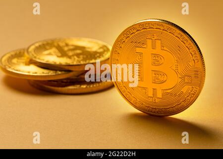 Close-up of a gold bitcoin in pile of coins. Virtual money or blockchain cryptocurrency. Large yellow copyspace. Stock Photo
