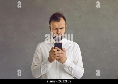 Serious businessman using smartphone standing over grey studio background Stock Photo
