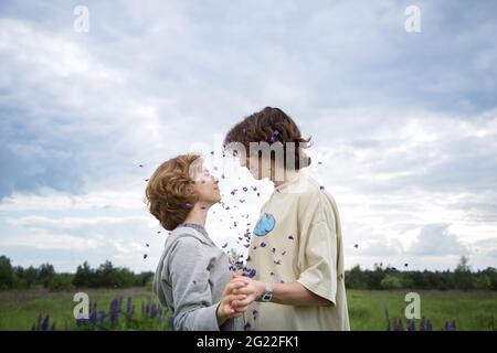 Two teenagers in love, girl and guy outdoors, stand opposite each other, hand in hand, look into eyes. atmospheric photo,carefree day, tenderness of r Stock Photo