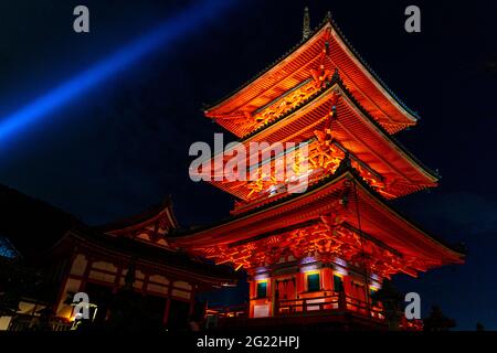 Kyoto, Japan - November 21, 2018 : Ancient red pagoda tower decorated by orange light under ceilings of Kiyomizu Dera temple at night. Stock Photo