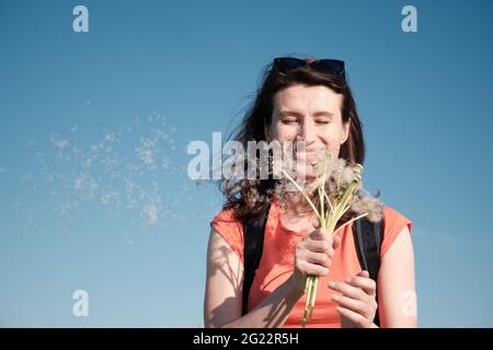 The girl blows the seeds off the dandelions. Stock Photo