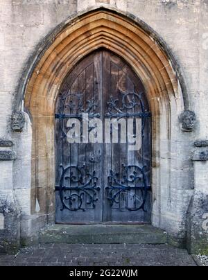 Large arched, ornate decorated door in Arundel Cathedral, with sculpted heads on either side; Arundel, West Sussex, UK Stock Photo