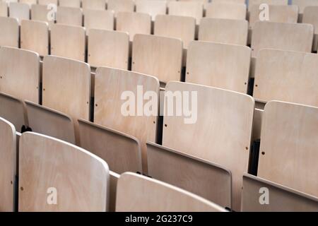 Empty collapsible wooden chairs in auditorium background. Higher education at university or college. Stock Photo