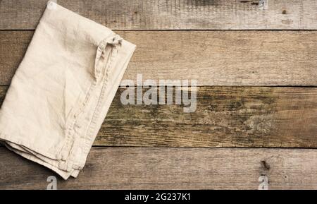 folded beige linen towel on a table made of old gray wooden boards, top view, copy space Stock Photo