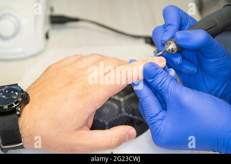 Men's manicure. Design of men's manicure. The master makes a man manicure. The concept of professional nail care. Close-up of the manicurist's hands a Stock Photo