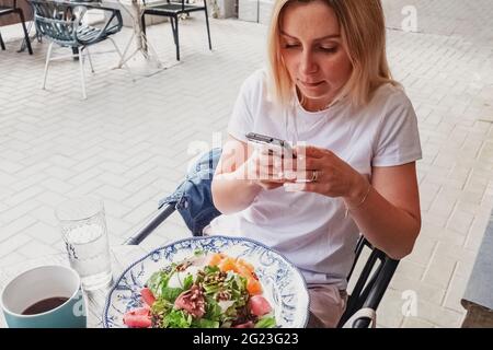 Woman sitting outside in cafe using her smartphone Stock Photo