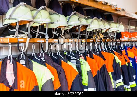 Helmets and uniforms in locker room of fire fighters Stock Photo