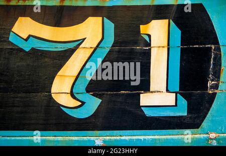 The weathered number 71 painted on the side of an old fishing boat moored at Girvan Harbour in South Ayrshire, Scotland.. Stock Photo