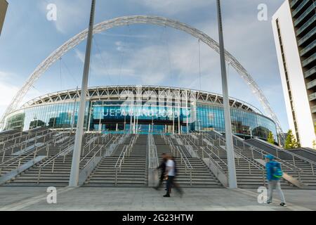 Wembley Stadium, Wembley Park, UK. 8th June 2021.  Passers by walk in front of Wembley Stadium and the newly constructed Olympic Steps ahead of UEFA Euro 2020.   Postponed by a year as the Coronavirus pandemic hit worldwide in 2020, the tournament starts in 3 days, 11th June 2021, with Wembley Stadium hosting it's first match, England v Croatia, on 13th June 2021.  Amanda Rose/Alamy Live News Stock Photo