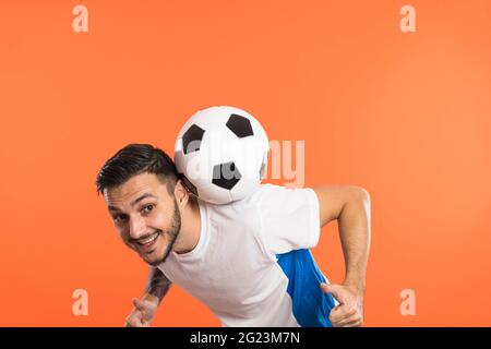 Football player do tricks with ball isolated on orange background Stock Photo