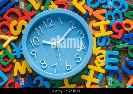 Blue alarm clock with colorful alphabet on wooden background Stock Photo