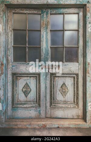 Ancient weathered double entrance door with cracked paint Stock Photo