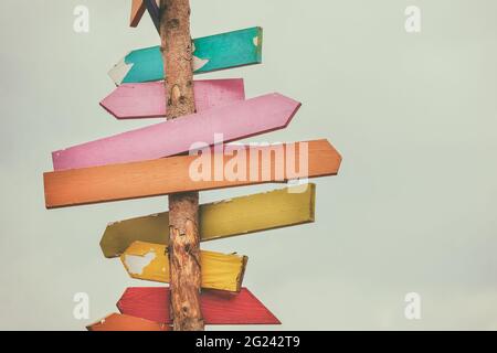 Colorful wooden direction arrow signs on a wooden pole Stock Photo