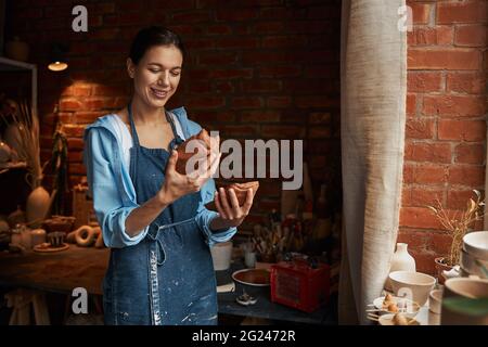 Beautiful young lady enjoy working with earthenware product in pottery studio Stock Photo