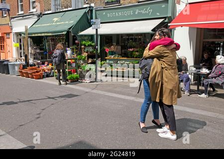 Women hugging in the street after covid restrictions ease in Exmouth Market street in Clerkenwell Borough of Islington London England UK  KATHY DEWITT Stock Photo