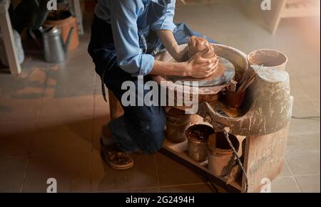 Charming female artisan wearing apron modeling clay pot in pottery workshop Stock Photo