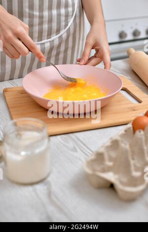 Woman beats eggs in a bowl. housewife cooking on kitchen Stock Photo