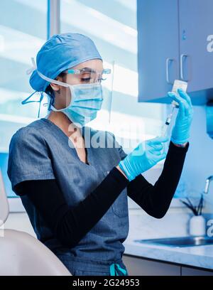 Nurse in face mask and shield preparing Covid-19 vaccination Stock Photo