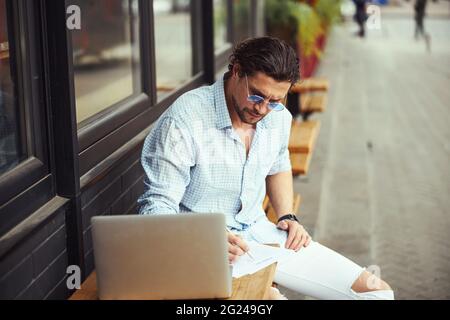 Busy freelancer making notes during online conference Stock Photo