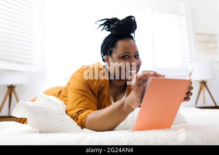 Smiling woman reading book in bed Stock Photo