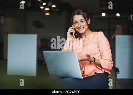 Young attractive elegant Caucasian female freelancer working online while using laptop in co-working space Stock Photo