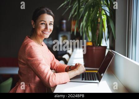 Young attractive brunette entrepreneur working at the laptop while surfing internet Stock Photo