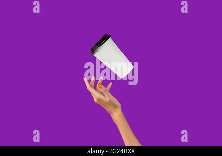 Womans hand with flying paper cup on purple background. Takeaway food and drink Stock Photo