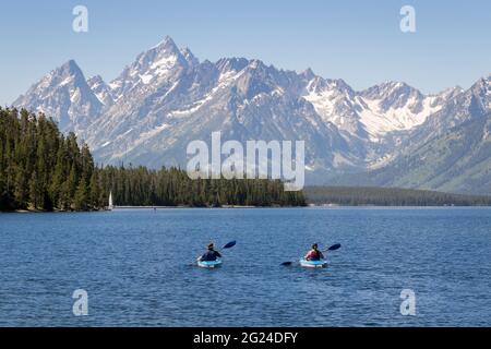 two people kayaking in Jackson Lake at Grand Teton National Park. Mountain range in background Stock Photo