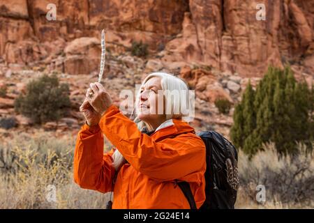 USA, Utah, Escalante, Woman looking at feather while hiking in Grand Staircase-Escalante National Monument Stock Photo