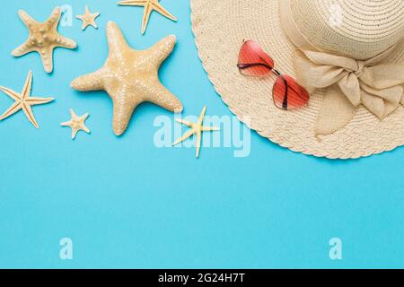 Various starfish, hat and sunglasses on a blue background with copy space. Stock Photo