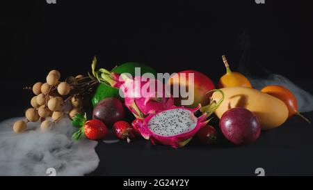 Exotic fruits in the white smoke on black Stock Photo