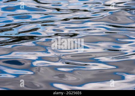 The waters of Weeks Bay in Alabama create an abstract pattern in blue, white and black. Stock Photo