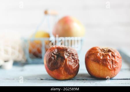 Two rotten apples on a table next to fresh ripe apples Stock Photo