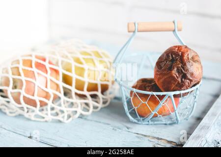 Two rotten apples on a table next to fresh ripe apples Stock Photo