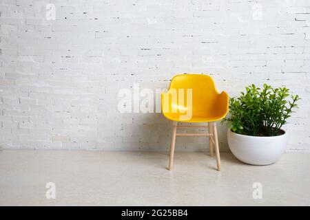 Yellow chair on the background of a white brick wall. Simple interior. Stock Photo