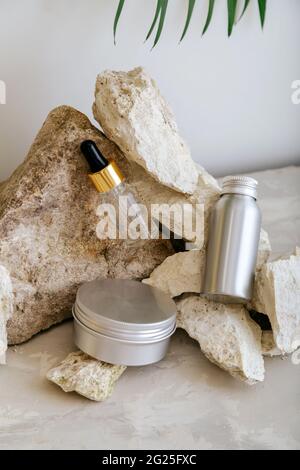 Set natural unisex beauty cosmetic skincare products for man in aluminum jars bottle on stone pedestal, balancing rock pile on gray background. Kit Stock Photo