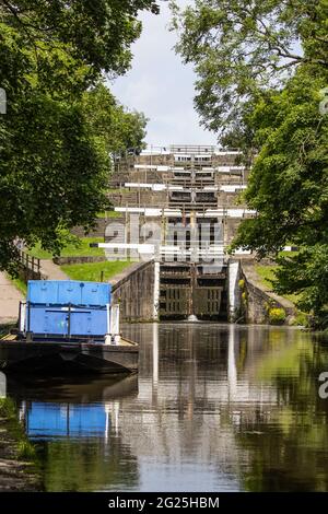 A barge waits at the foot of the five-rise locks in Bingley on the Leeds & Liverpool canal in West Yorkshire, England Stock Photo