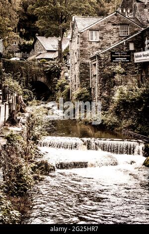 A view of Stock Ghyll Force as it flows over a waterfall in to the town of Ambleside in the Lake District, Cumbria UK Stock Photo