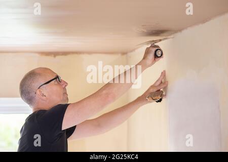 Male Plasterer Plastering Ceiling In Room Of House Stock Photo