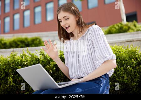 Young Female College Student OR Office Worker With Laptop Having Video Chat Outdoors On College Campus Stock Photo