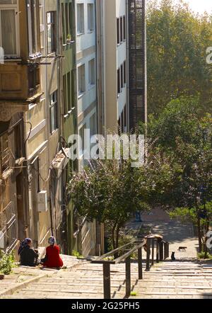 Turkish Street scene in the Fath area of Istanbul, Turkey. Turkisj women sitting on steep street steps. Stock Photo