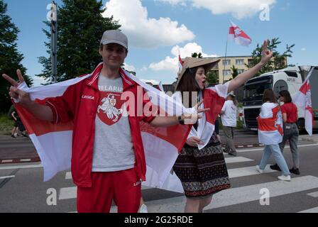 Warsaw, Warsaw, Poland. 8th June, 2021. A man holds a historical Belarus opposition flag and gestures victory signs in the ongoing protest at the Polish-Belarusian crossing on June 8, 2021 in Bobrowniki, Poland. Around a hundred of Belarusian dissidents protest at the border crossing to demand the European Union to impose economic sanctions against the Belarusian President Alexander Lukashenko, after dissidents were detained on a Ryanair flight that has been forced to land and most Belarusian citizens are now banned from leaving the country. Credit: Aleksander Kalka/ZUMA Wire/Alamy Live News Stock Photo