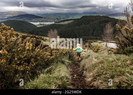Curly haired boy happily walking on trail in New Zealand with arms extended Stock Photo