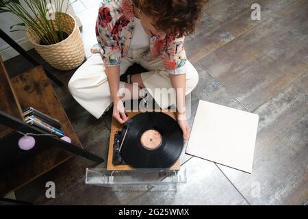 Young woman playing a vinyl record on a turntable at home Stock Photo