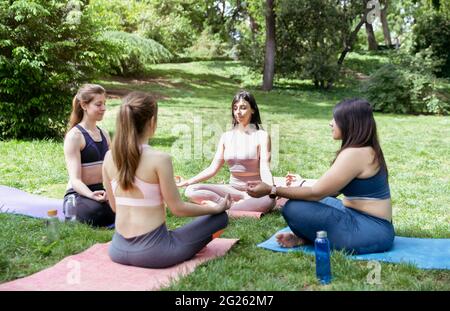 Four young girls doing meditation exercises during outdoor yoga class. Stock Photo