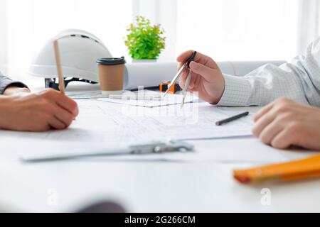 The team of architects is working on the sketches of the blueprints for the project. Engineers create a room design by drawing on paper. Stock Photo